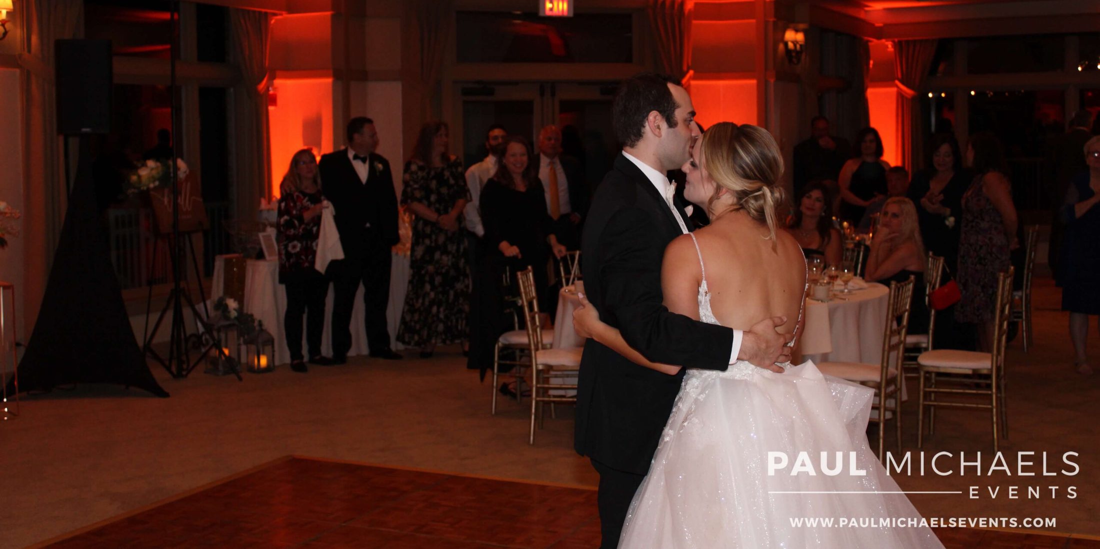 Golf course wedding DJ services provided for bride and groom, slow dancing in room with amber uplighting