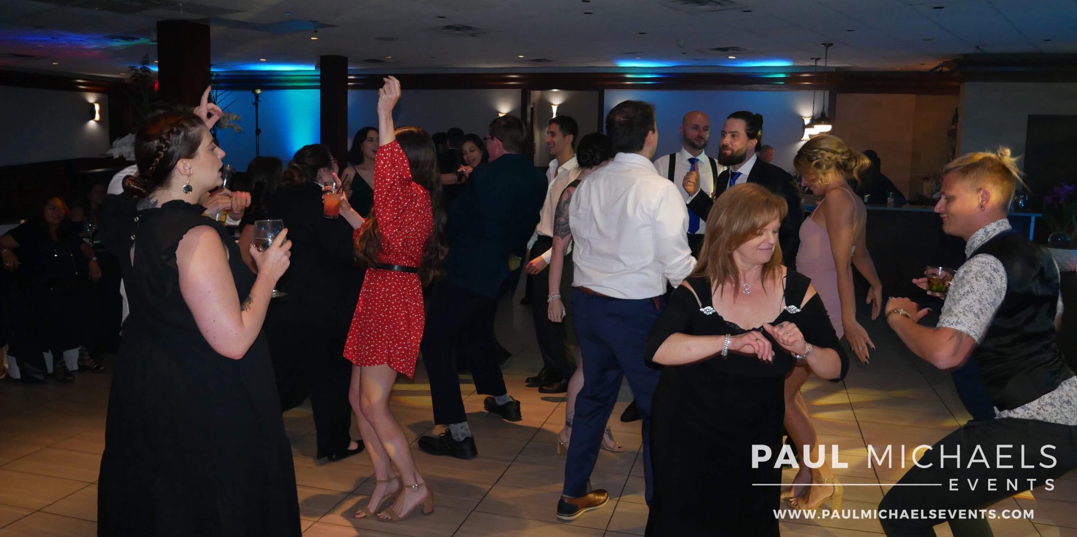 Group of people on the dance floor at a wedding, dancing, having a good time, enjoying DJ services