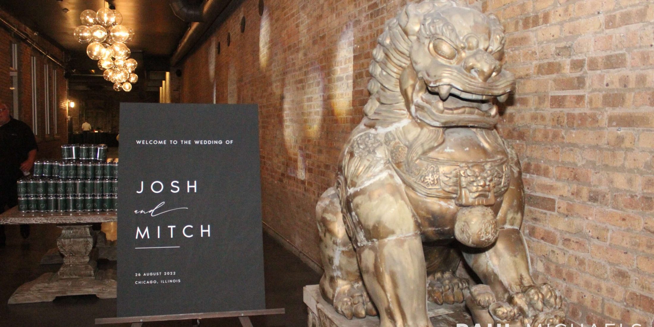 Sign that reads "Welcome To The Wedding Of Josh and Mitch 26 August 2022 Chicago, Illinois", next to a statue of an animal
