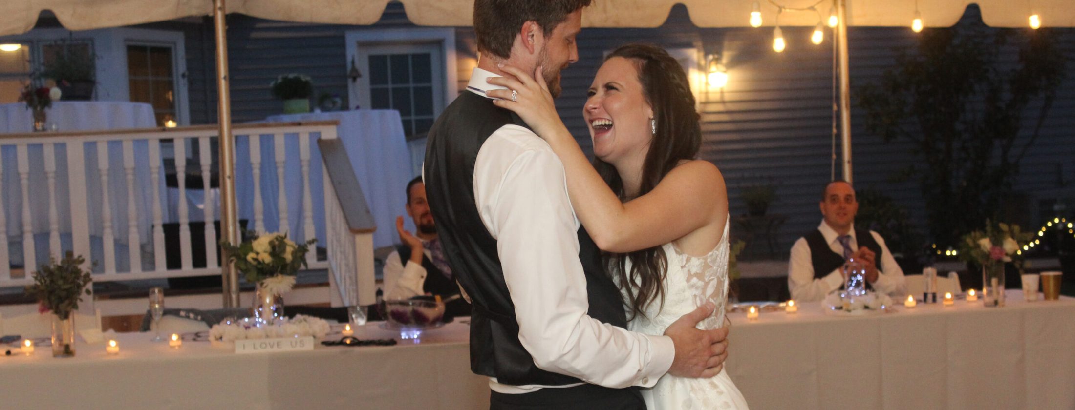Bride and groom's first dance, groom's hands on the bride's hips, the bride's hands around the groom's neck, both laughing and cheerful