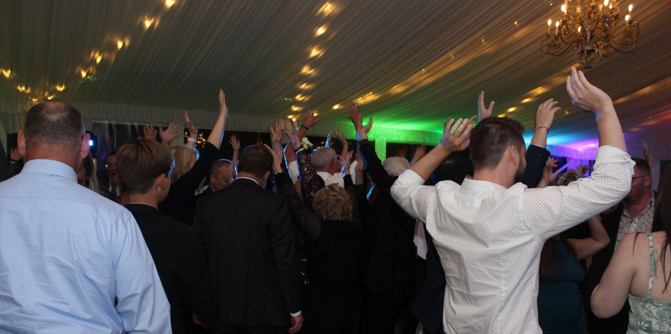 Photo of people on the dance floor with their hands in the air, dancing to music by Paul Michaels Events, a Chicago Suburbs Wedding DJ