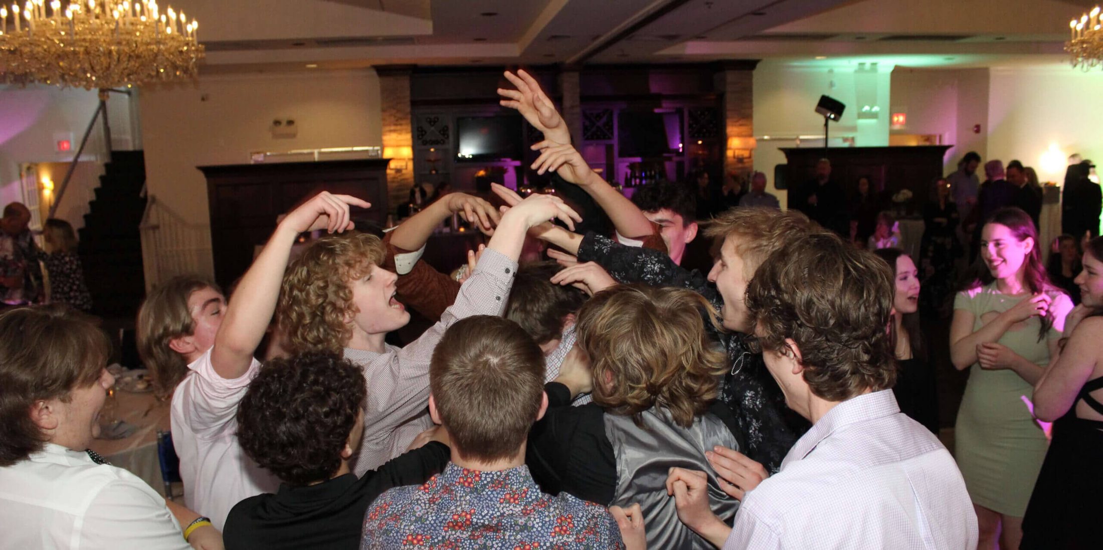 Photo of group of young people in the middle of the dance floor with their hands in the air, dancing to the Best Sweet 16 Chicago DJ at Ruffled Feathers Golf Club in Lemont, Illinois