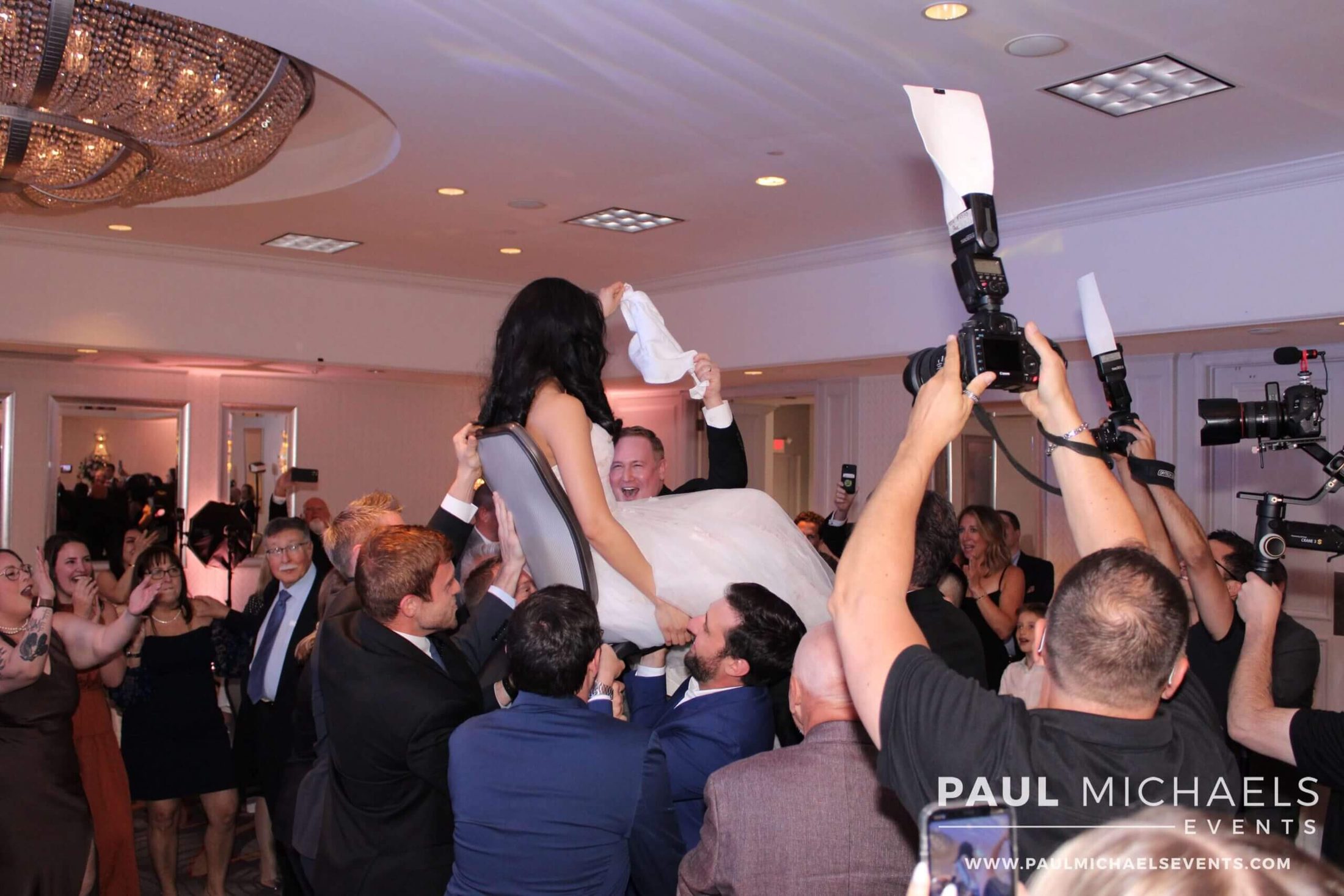 Bride and groom doing the traditional Horah dance with their guests, with expert DJ services provided by Paul Michaels Events