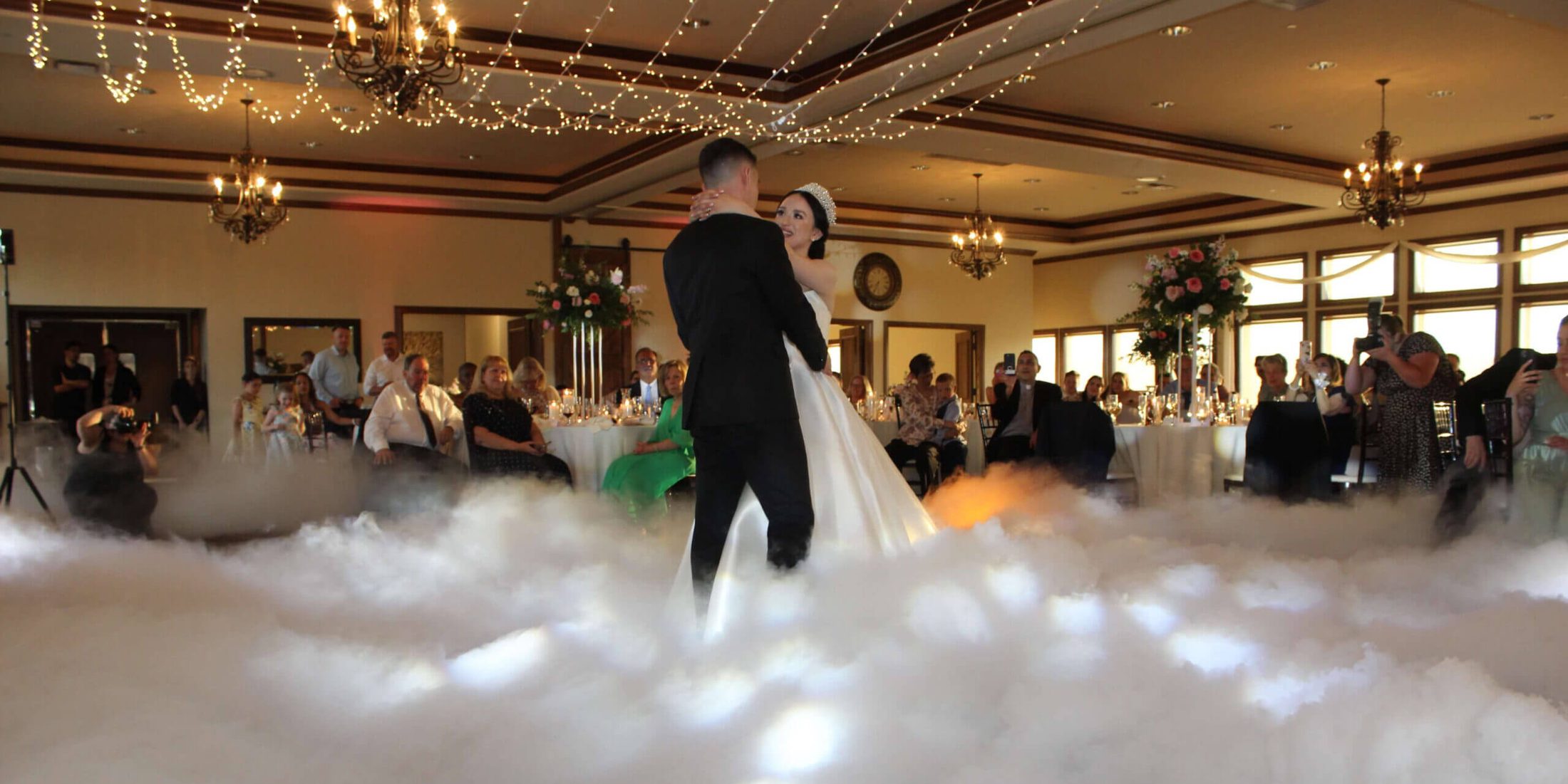 A bride and groom sharing their first dance with a "dancing in the clouds" effect, courtesy of the premium DJ services from Paul Michaels Events