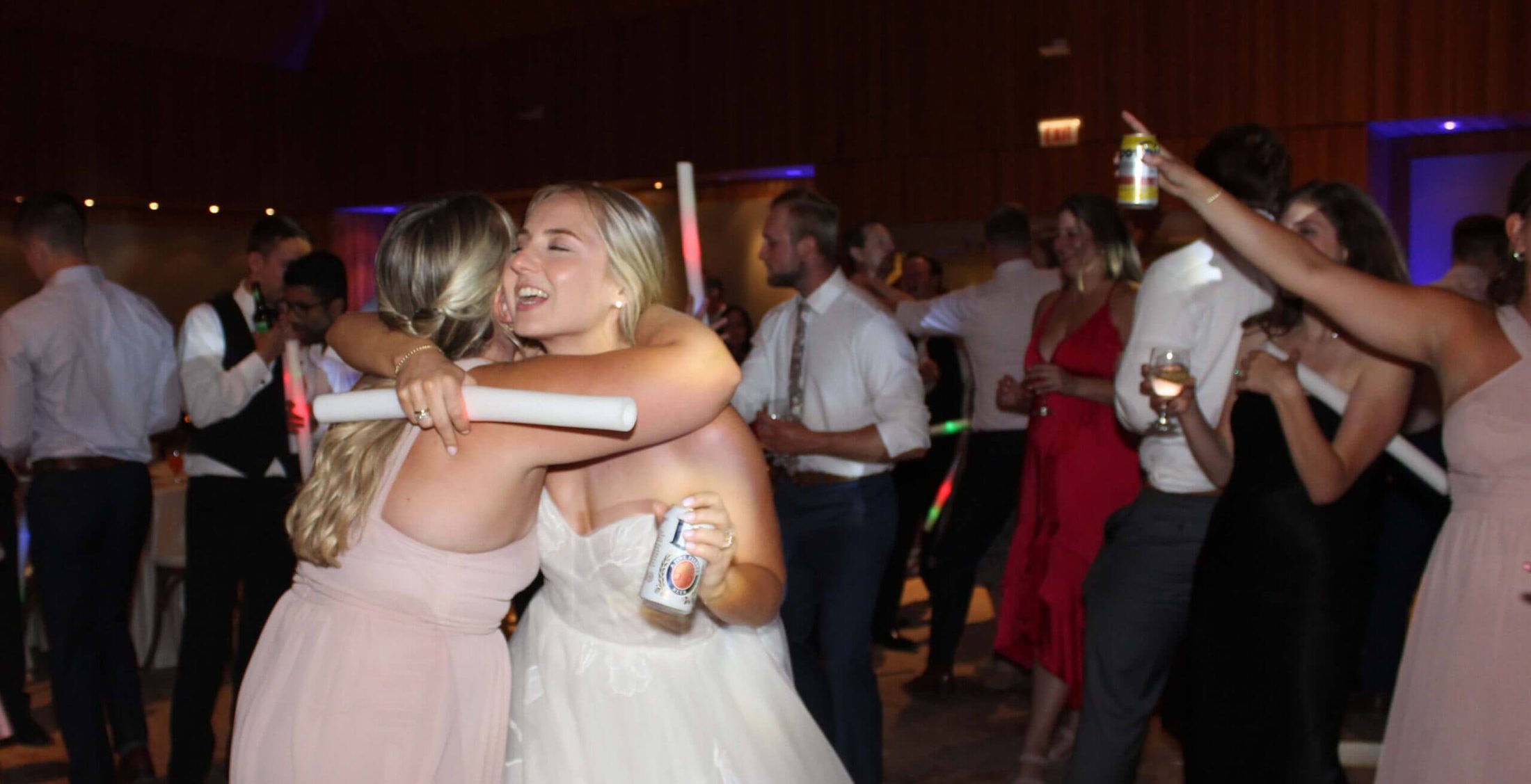 A bride hugging one of her bridesmaids in the middle of the dance floor, dancing the night away to one of the best Chicagoland wedding entertainment DJs, Paul Michaels Events