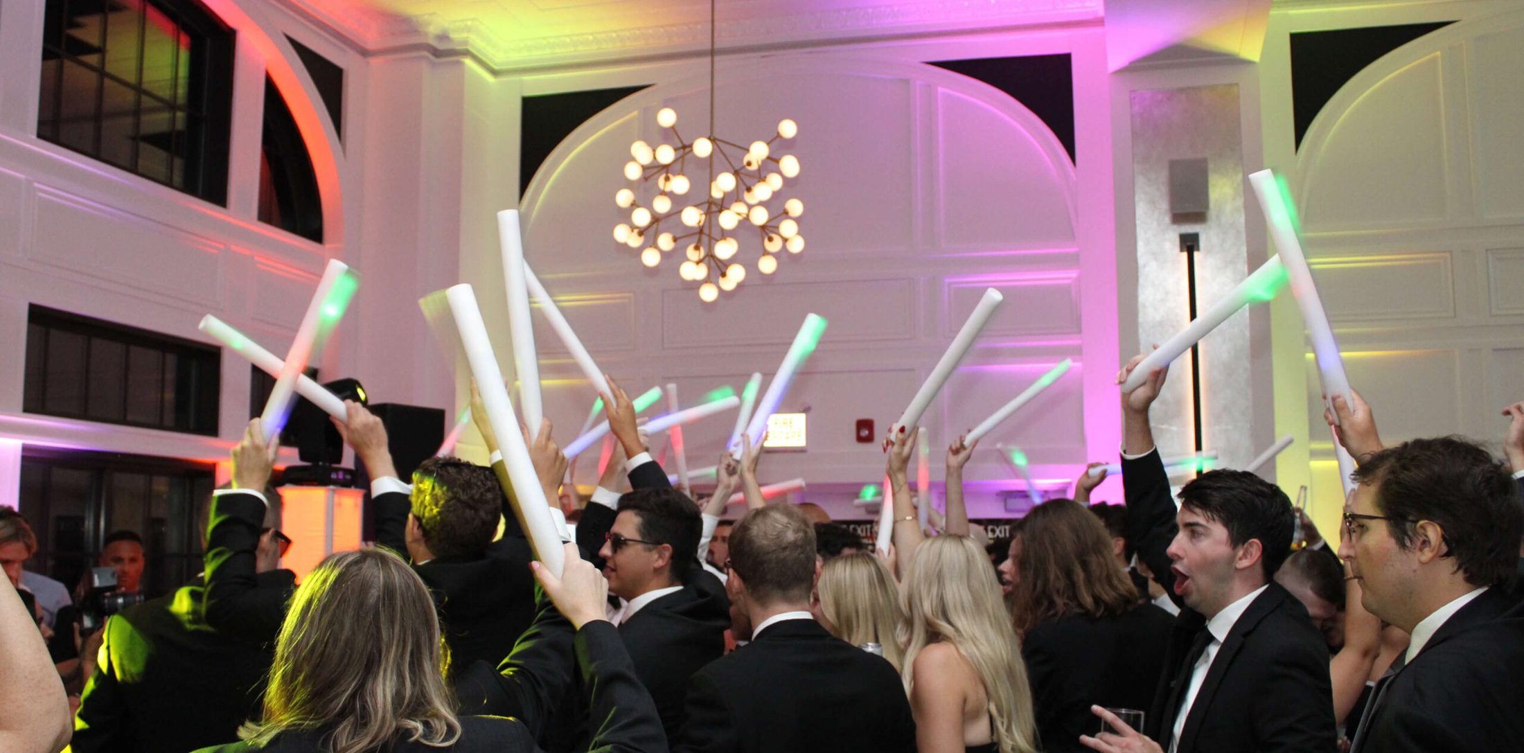 Group of people waving glow sticks on the dance floor