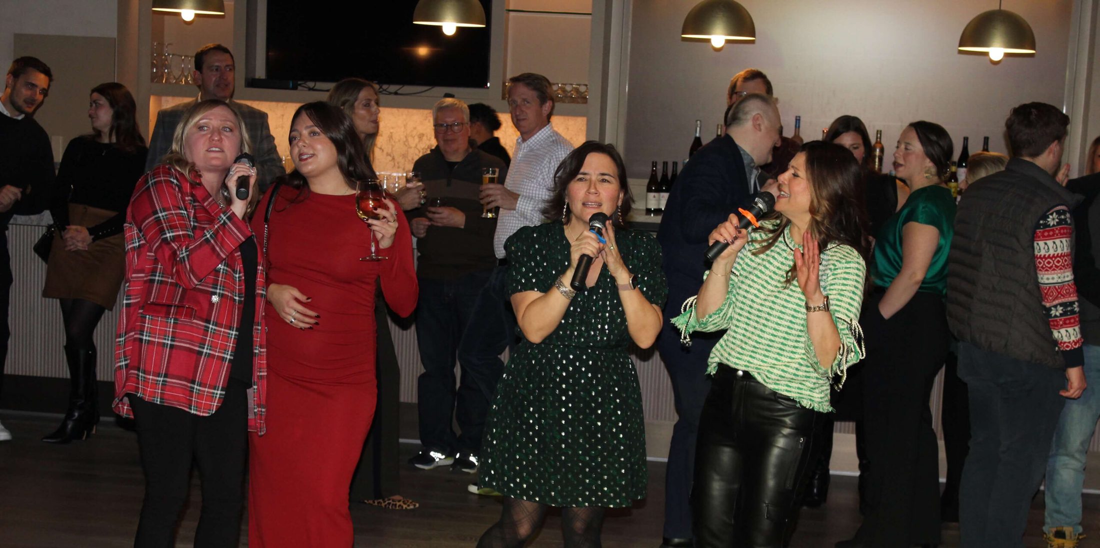 Group of ladies singing karaoke at corporate holiday party