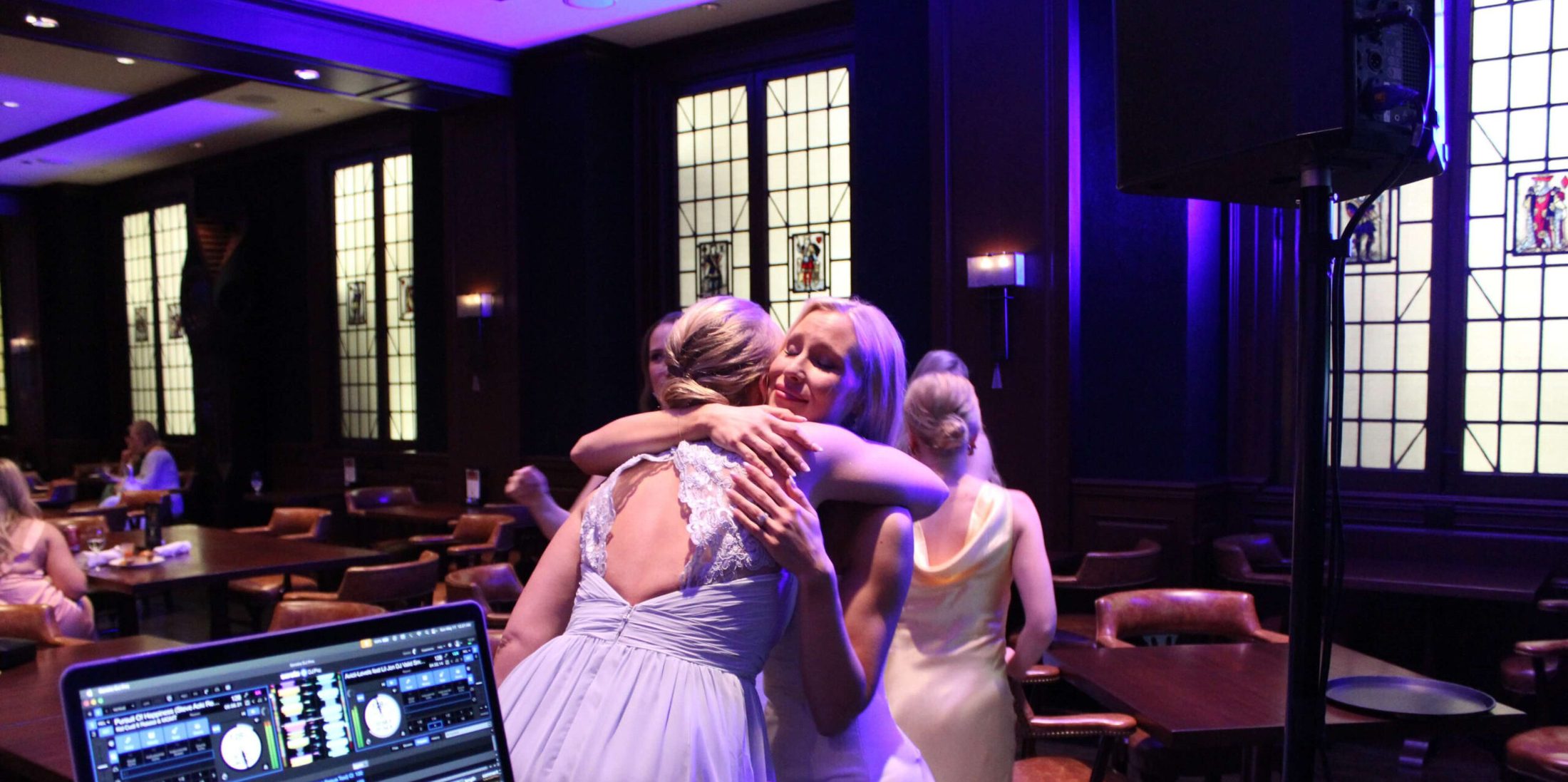 Bride and guest hugging on the dance floor with music