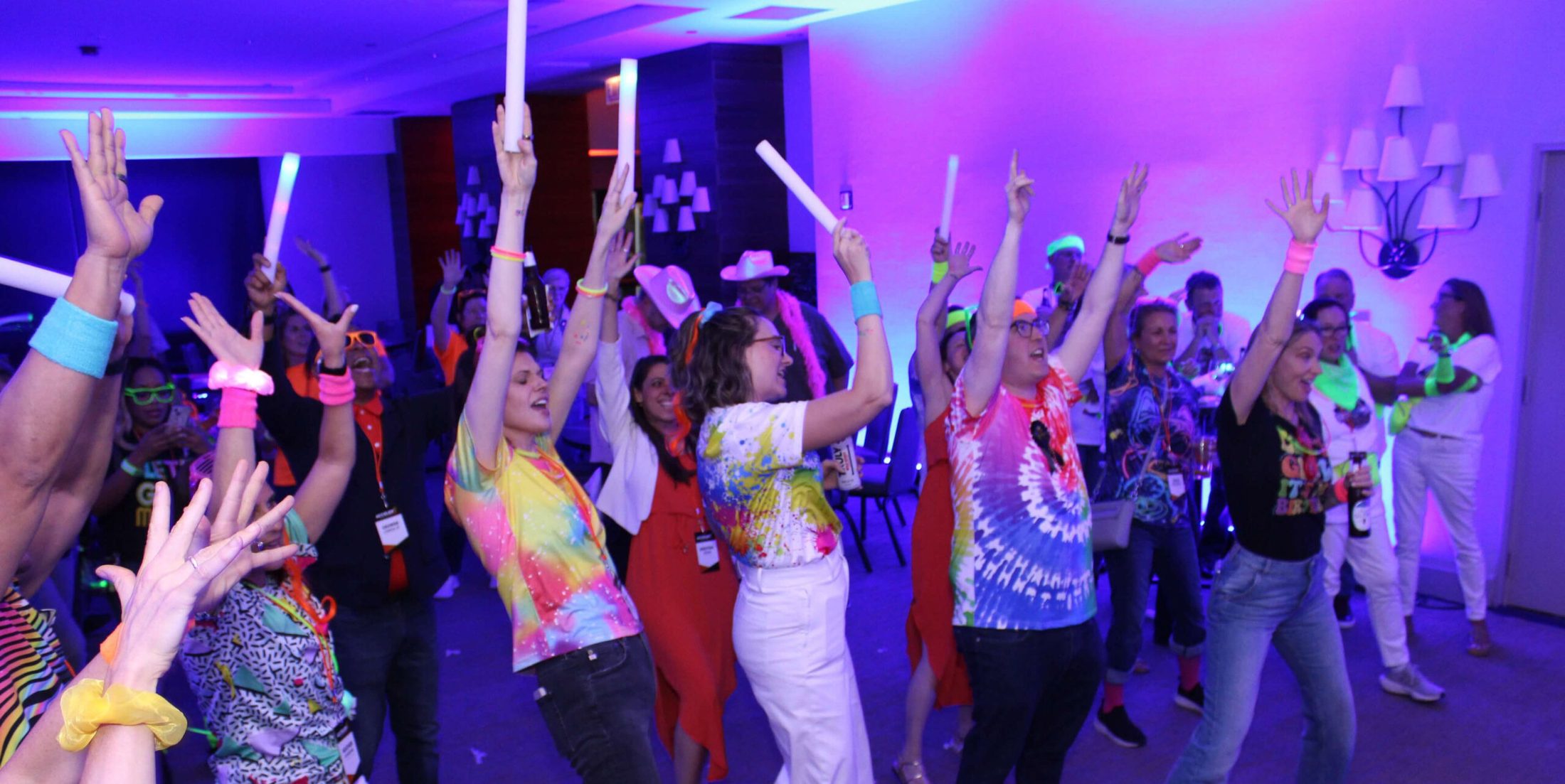 A group of people with hands and glow sticks in the air.