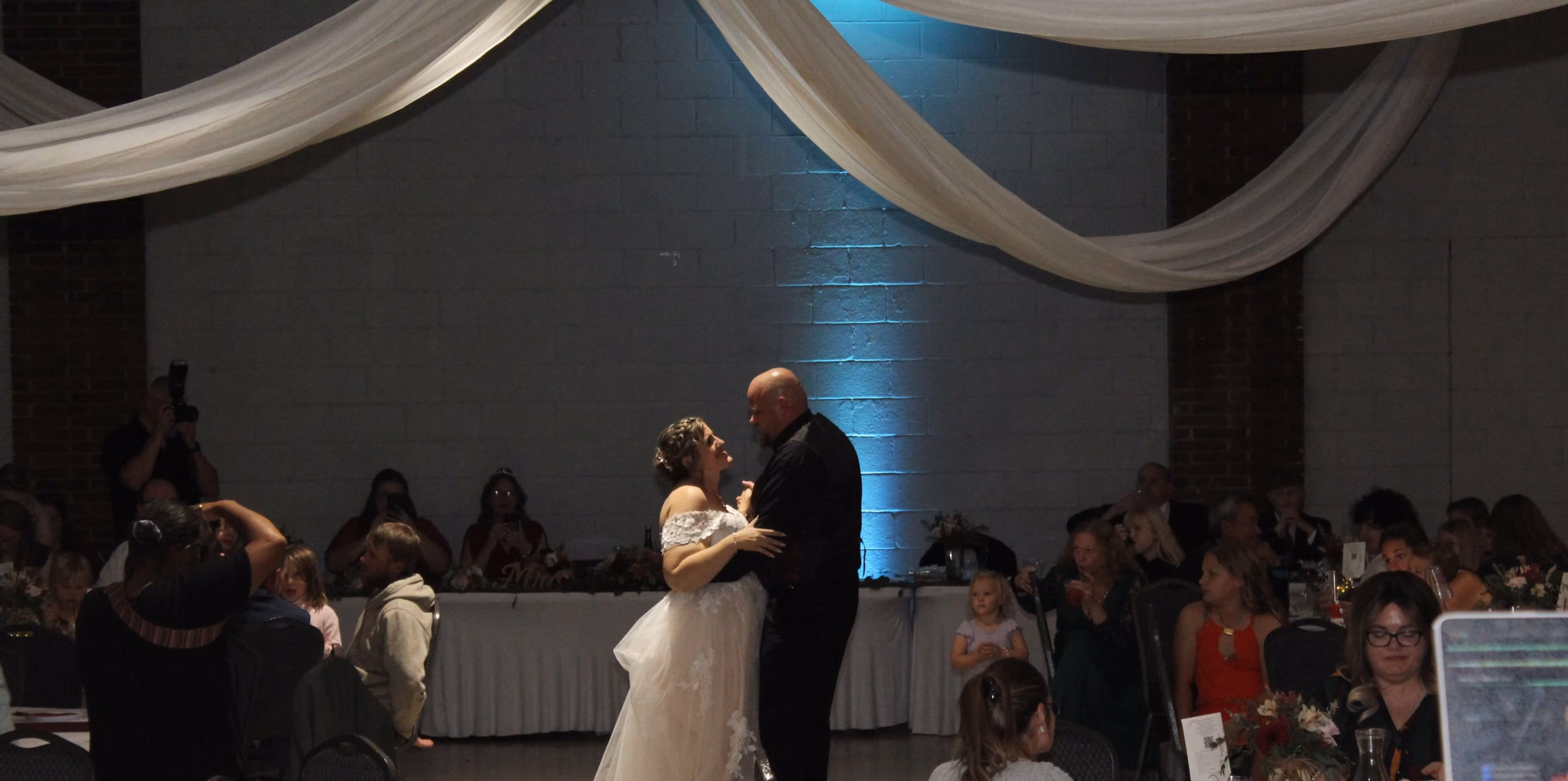 Bride & groom sharing first dance surrounded by loved ones